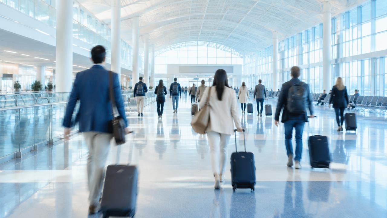 Travelers walking through a spacious airport concourse.